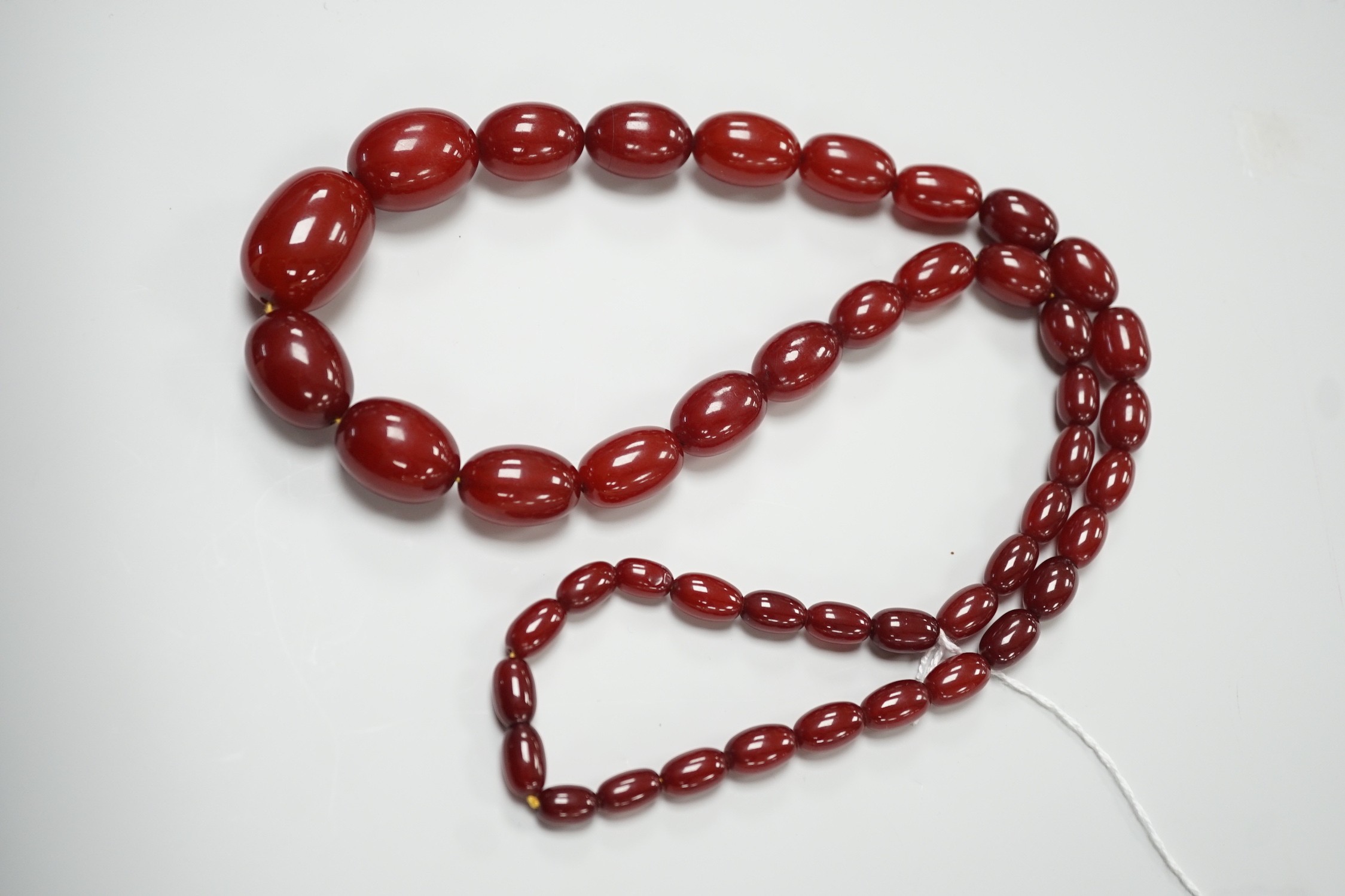 A single strand graduated simulated oval cherry amber necklace, 82cm, gross weight 113 grams.